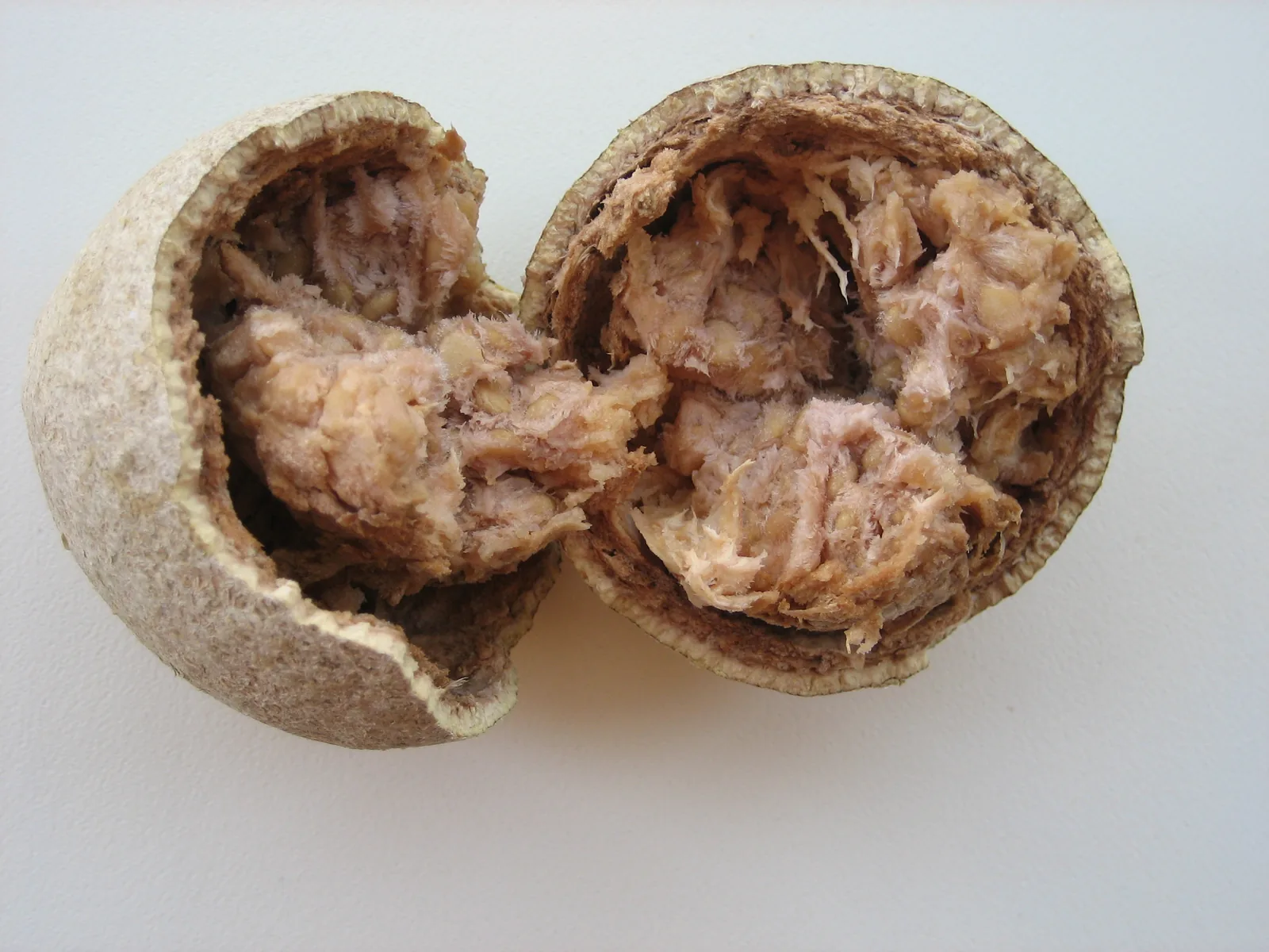 A whole wood apple cracked open beside a bowl of kaitha powder